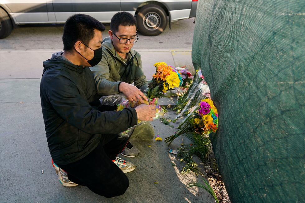 Two men place flowers near Star Dance Studio to honor victims killed in a shooting in Monterey...
